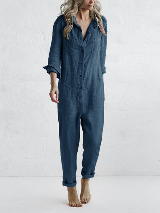 Stijlvolle blauwe katoenen jumpsuit met lange mouwen, knoopsluiting en zakken. Comfortabel en veelzijdig kledingstuk voor diverse gelegenheden, gedragen door een model met blond haar.