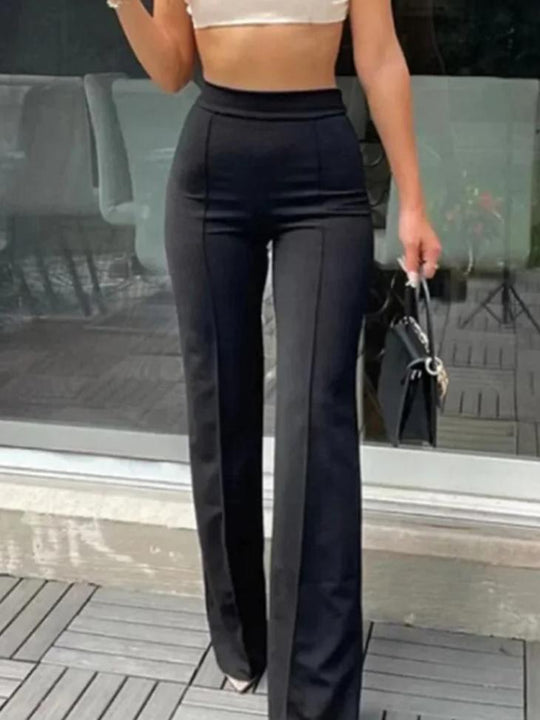 Elegante zwarte flared broek met hoge taille, accentueert vrouwelijke vormen en verlengt silhouet. Gedragen met witte crop top en zwarte handtas voor een stijlvolle look. Perfecte combinatie van comfort en mode voor diverse gelegenheden.